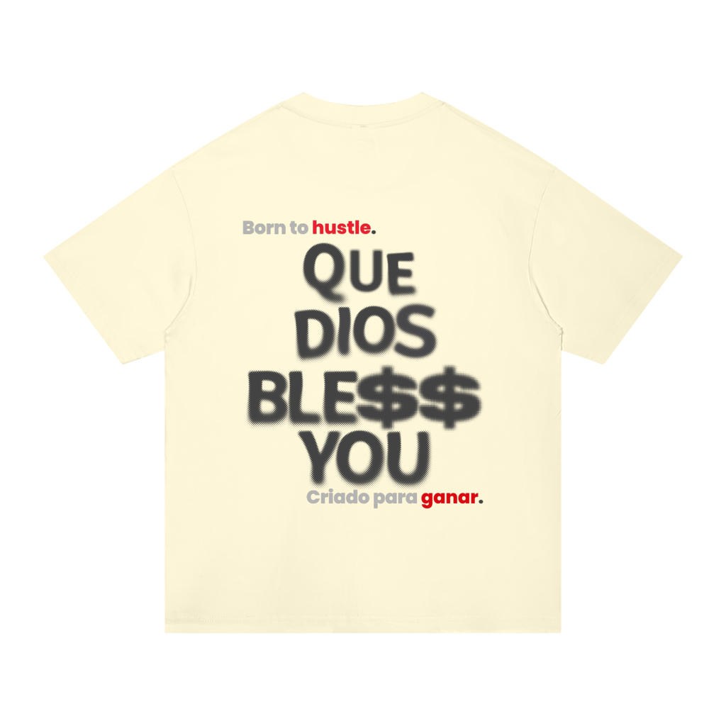 A pale cream-colored t-shirt shown from the back, featuring a Spanish graphic print that reads 'Born to hustle. QUE DIOS BLESS$ YOU / Criado para ganar.
