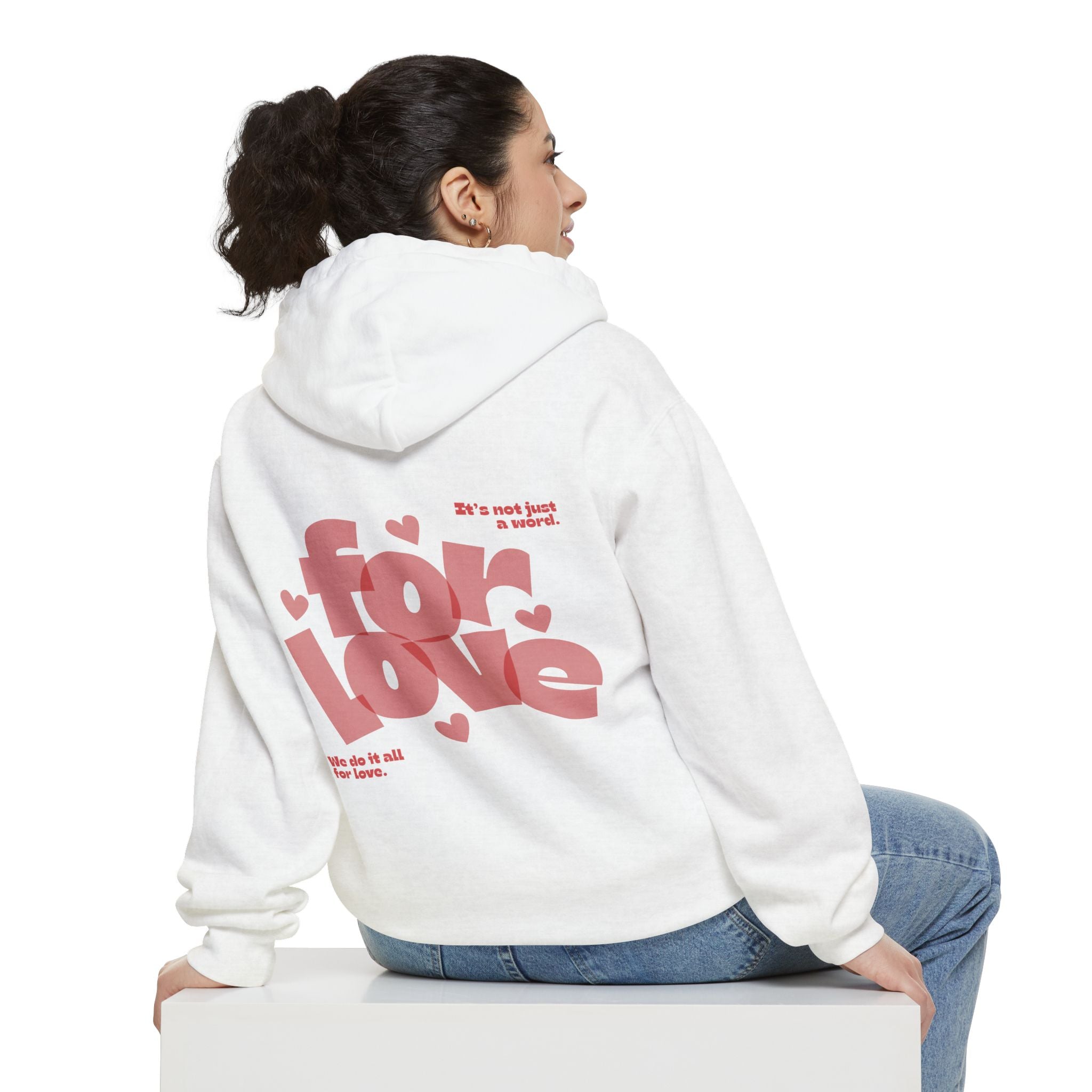 Person wearing a white hoodie with red text on the back, sitting on a white surface.