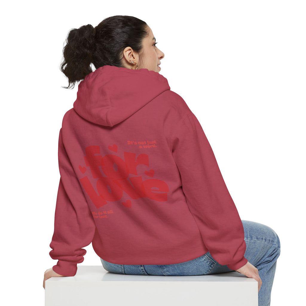 Person wearing a red hoodie with text on the back, sitting on a white box against a white background