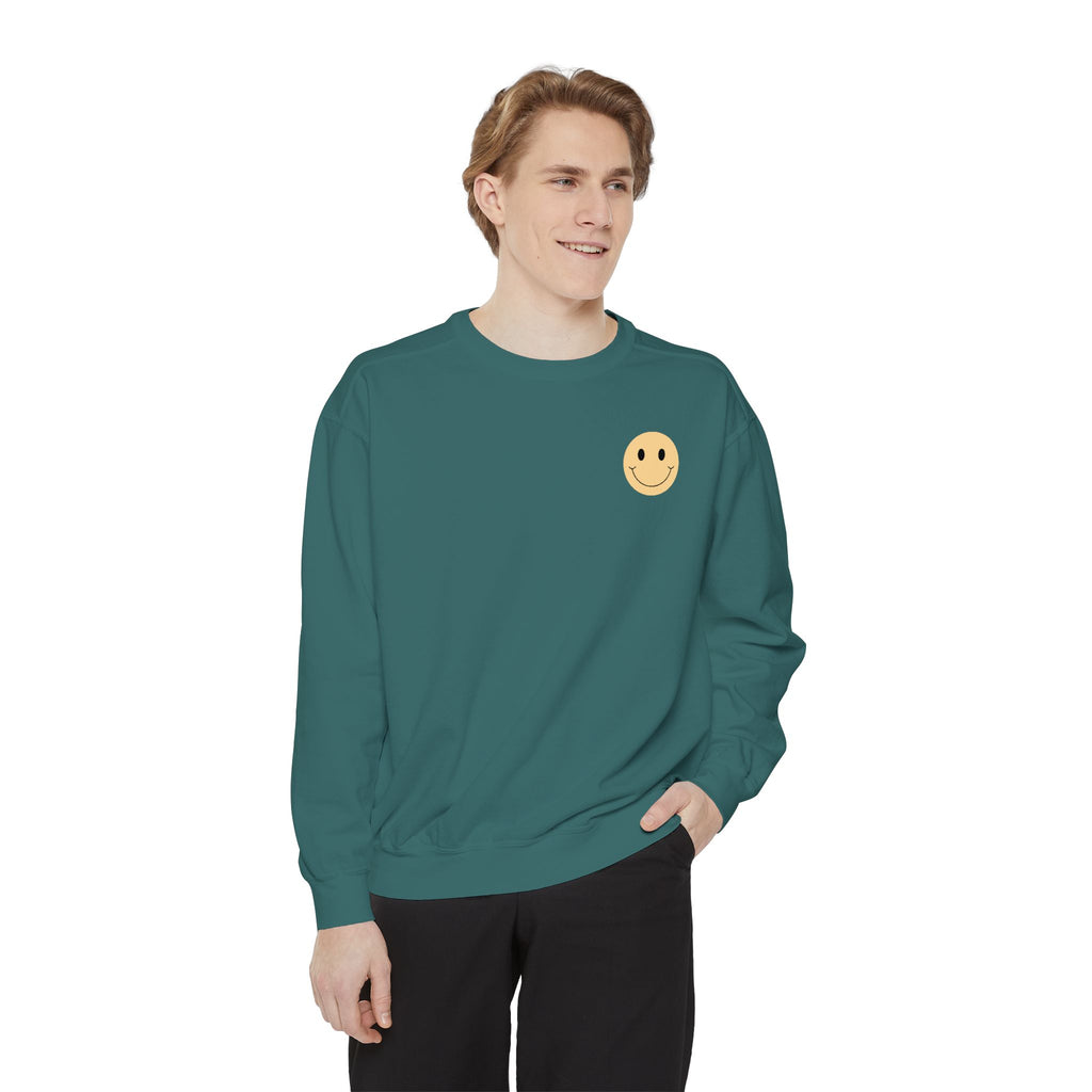 Man wearing a green sweatshirt with a smiley face emblem on a white background