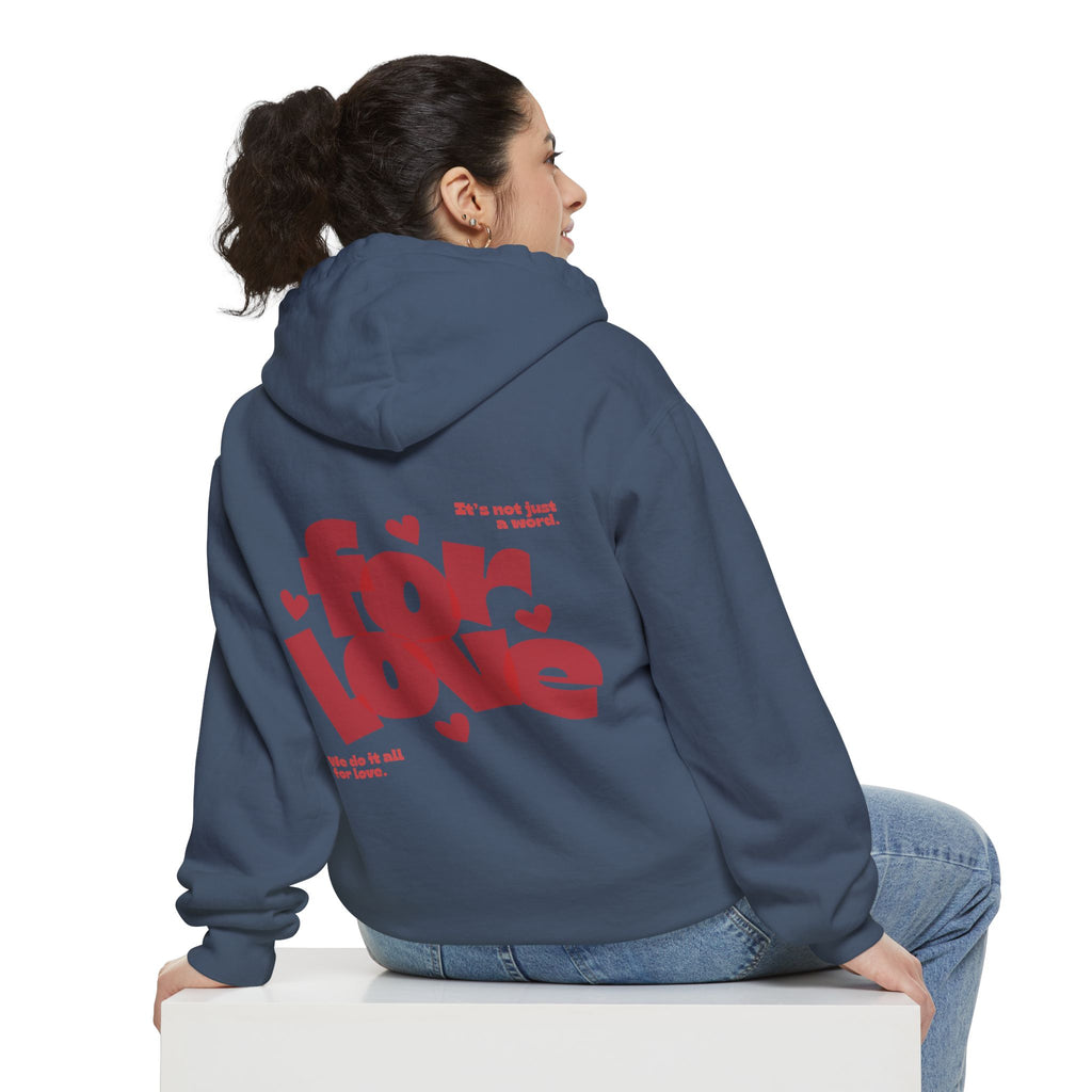 Person wearing a blue hoodie with red text on the back, sitting on a white cube against a white background