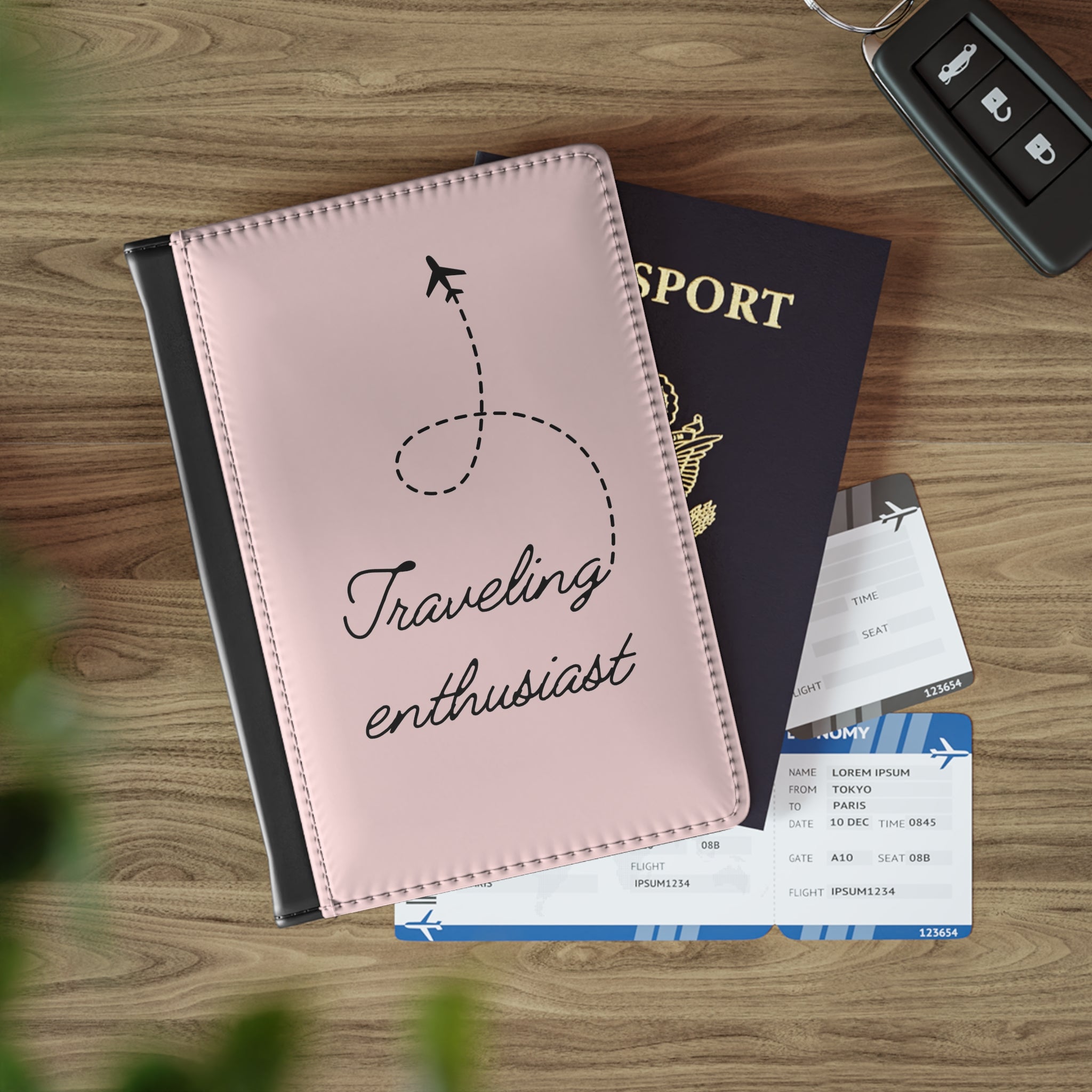 Pink travel journal with 'Traveling enthusiast' text, passport, and airplane tickets on a wooden surface.