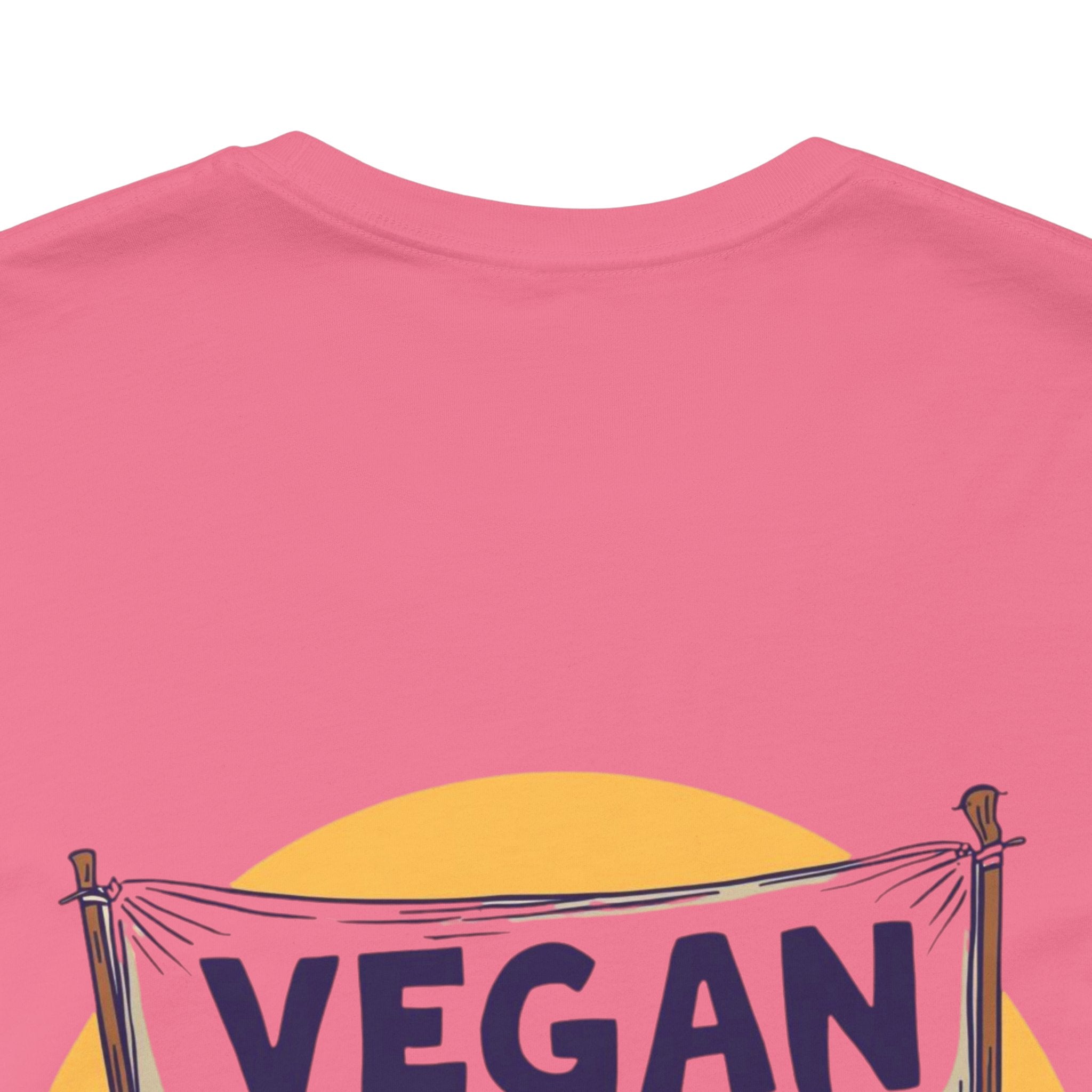 Pink t-shirt with a 'VEGAN' banner design on a white background