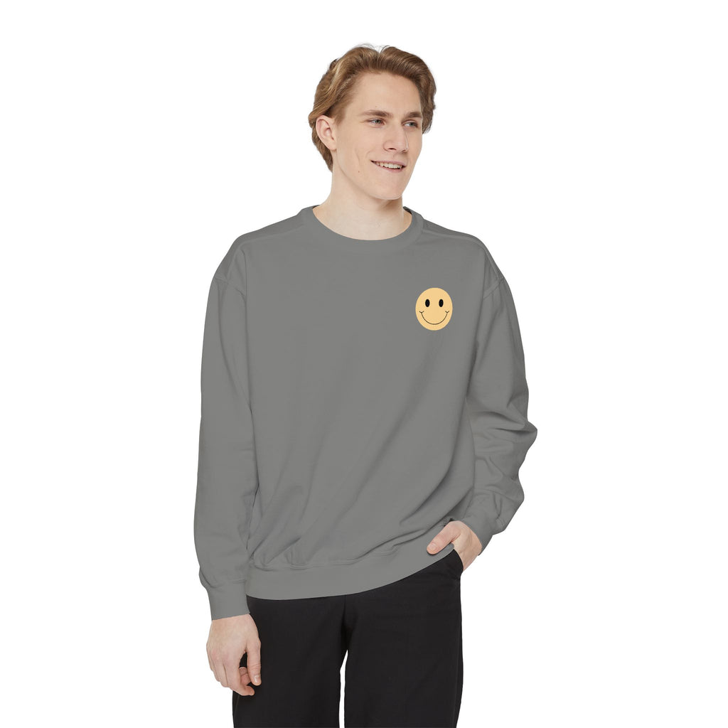 Person wearing a gray sweatshirt with a smiley face emblem on a white background
