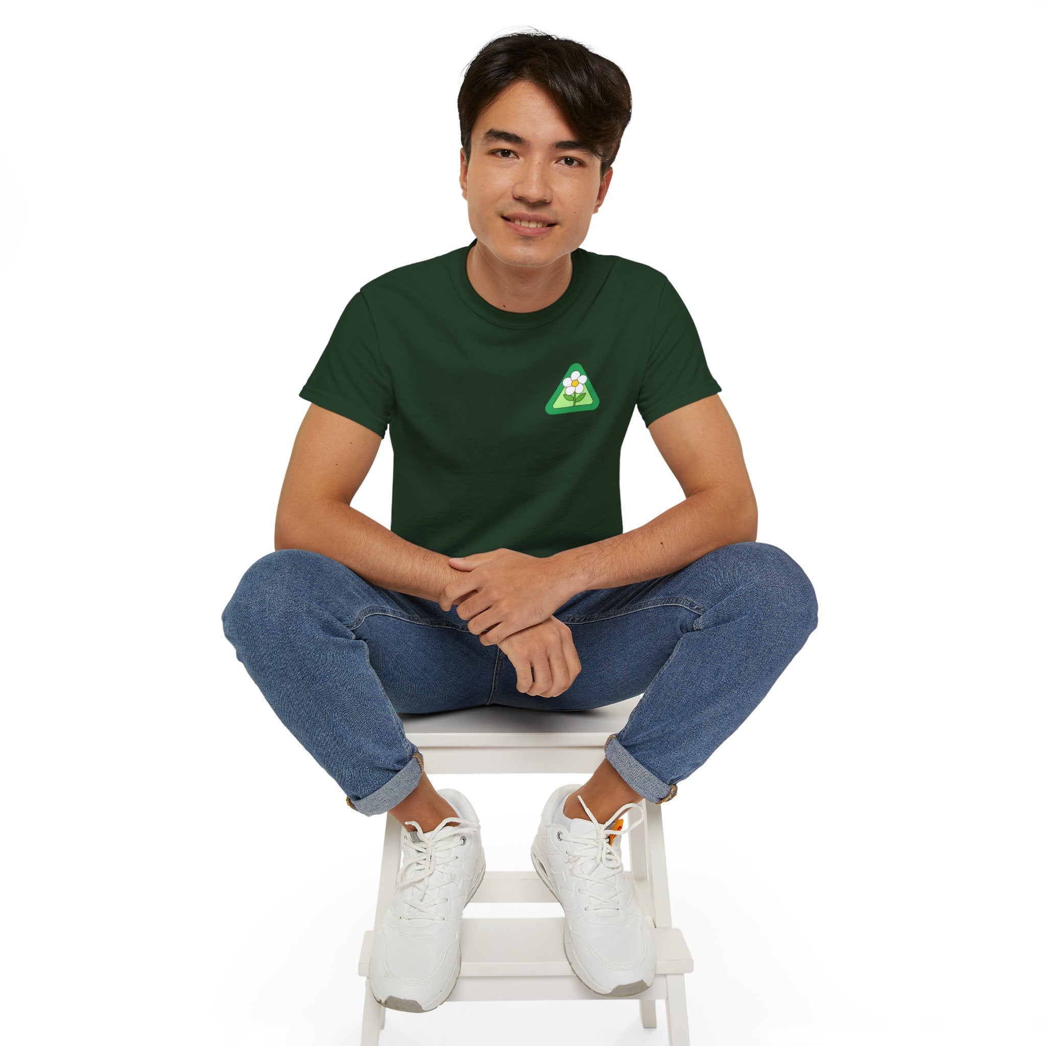 Person wearing a green t-shirt with a logo, sitting on a white stool against a white background