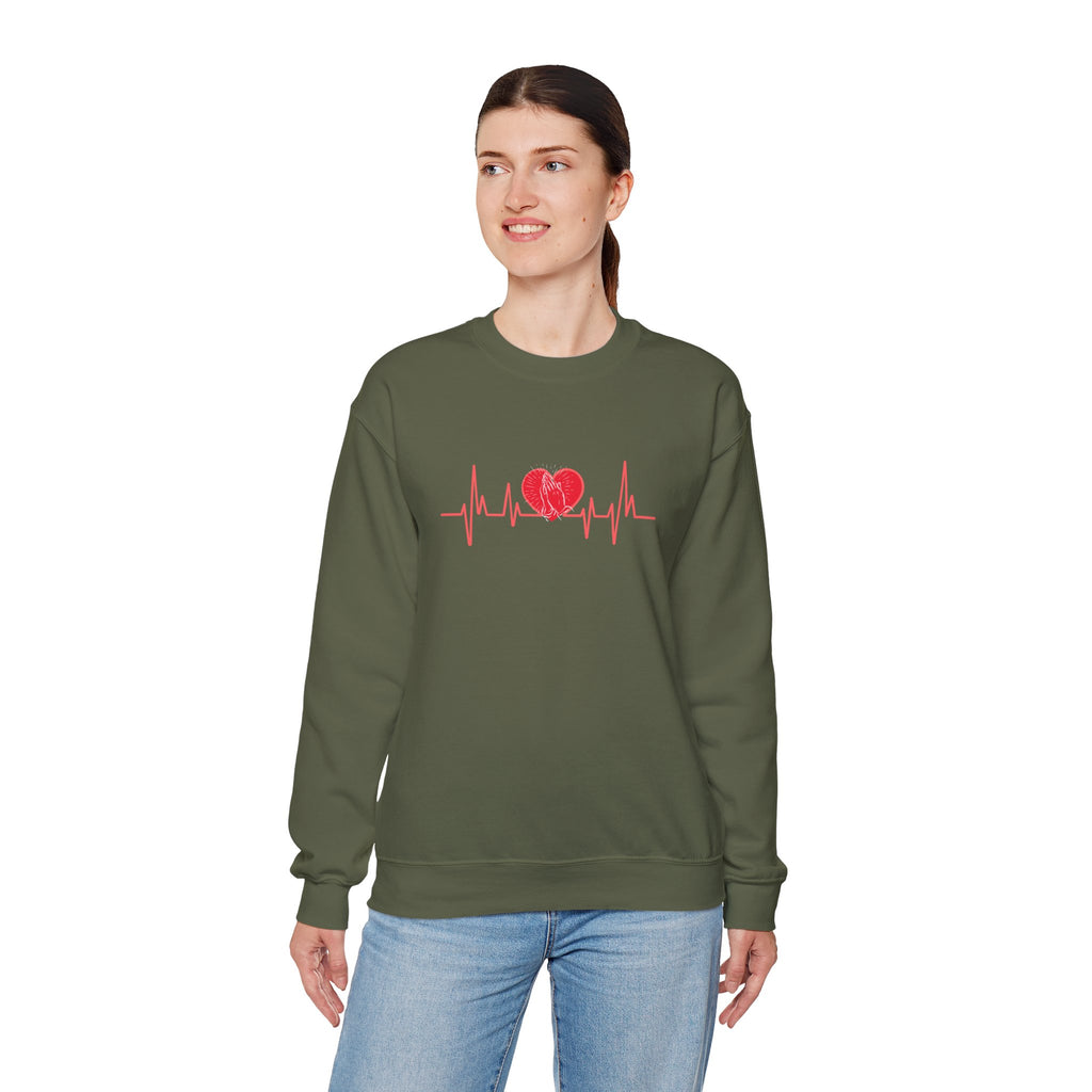 Person wearing a green sweatshirt with a red heart and heartbeat line design on a white background
