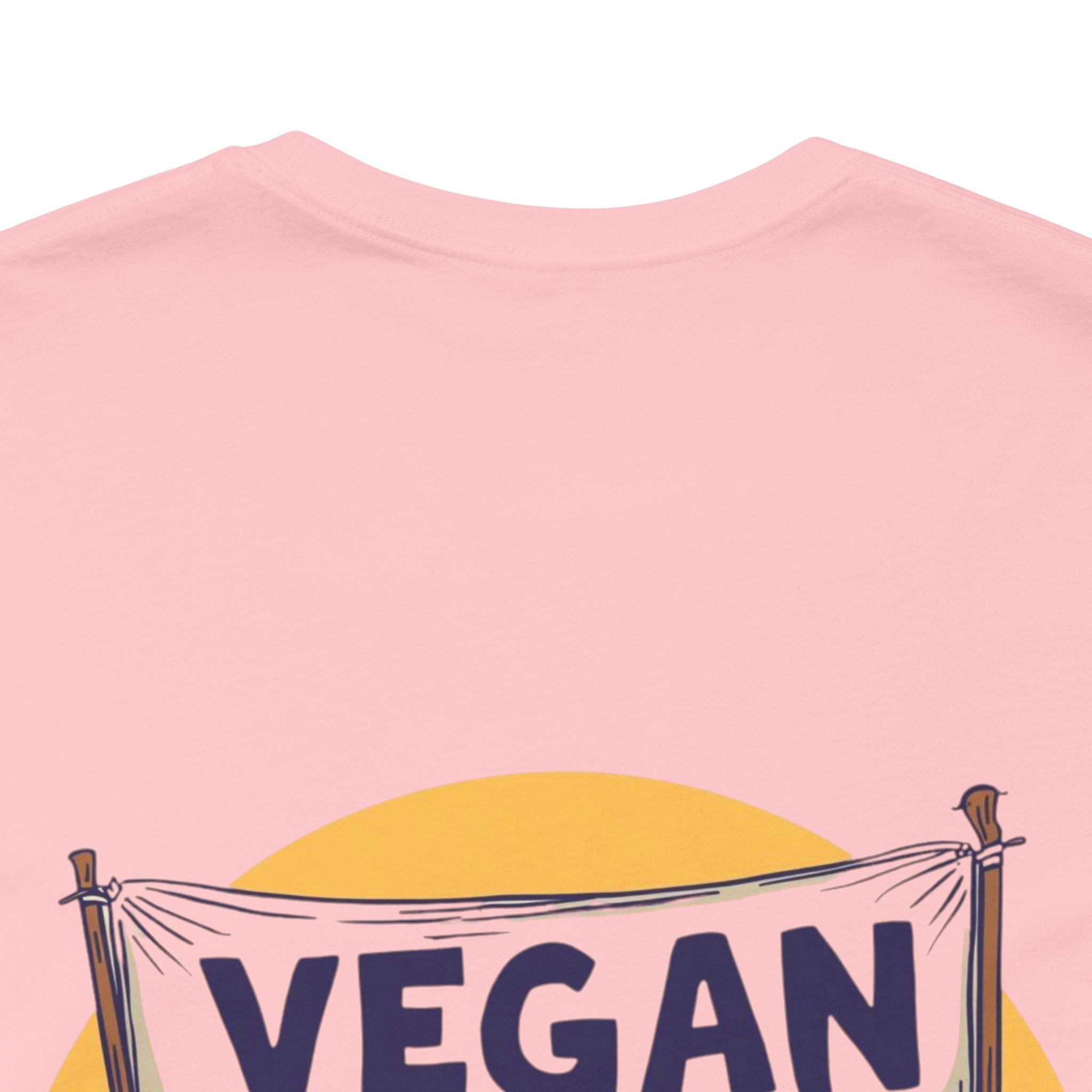 Pink t-shirt with 'VEGAN' banner design on a white background