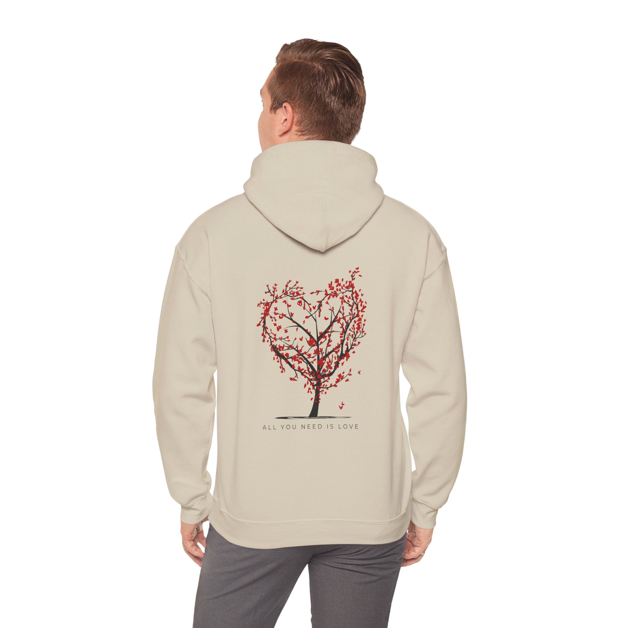 Person wearing a beige hoodie with a tree design on the back against a white background
