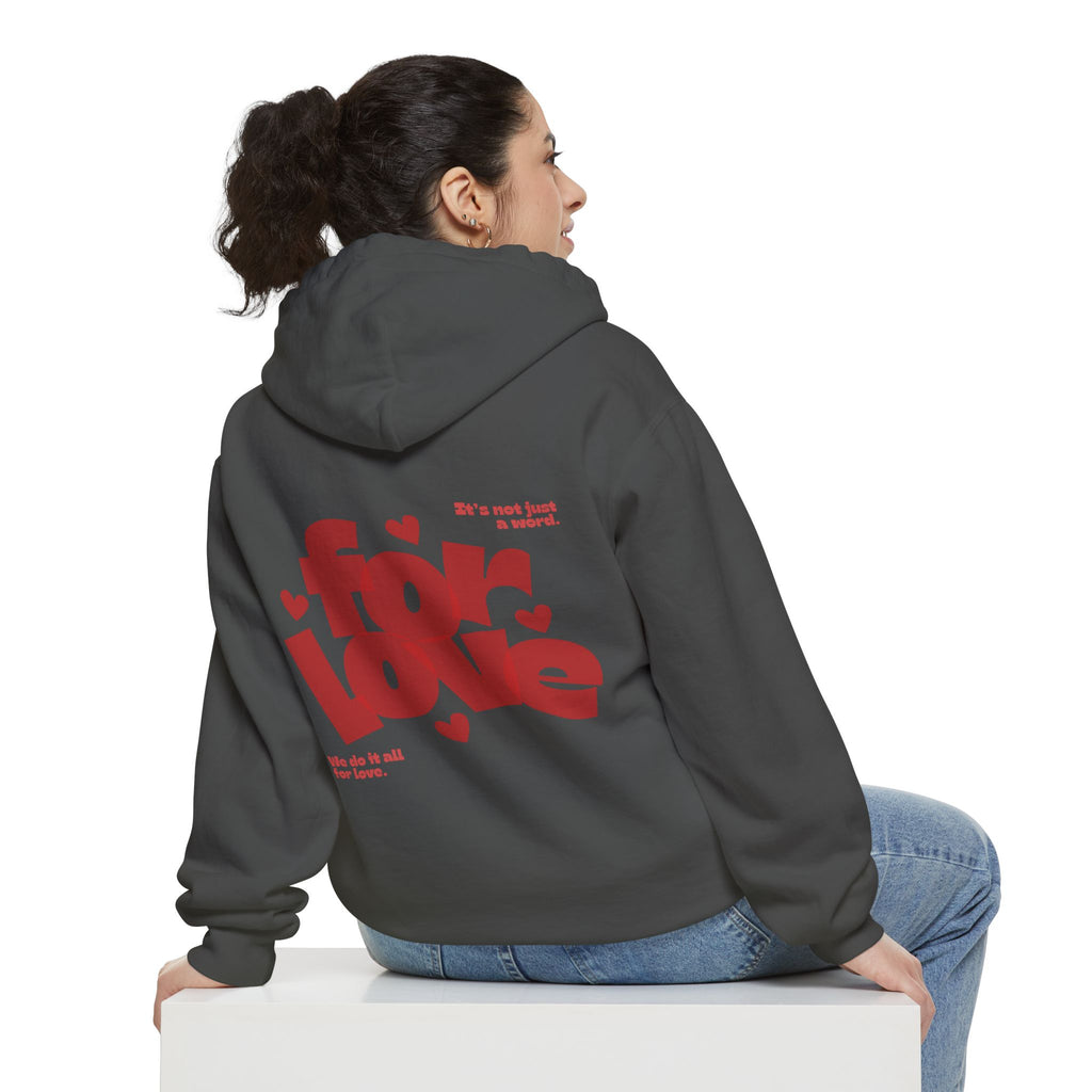 Person wearing a gray hoodie with red text on the back, sitting on a white box against a white background.