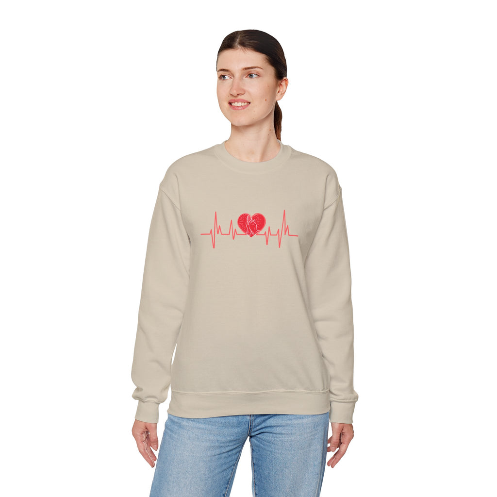 Woman wearing a beige sweatshirt with a red heart and line design on a white background