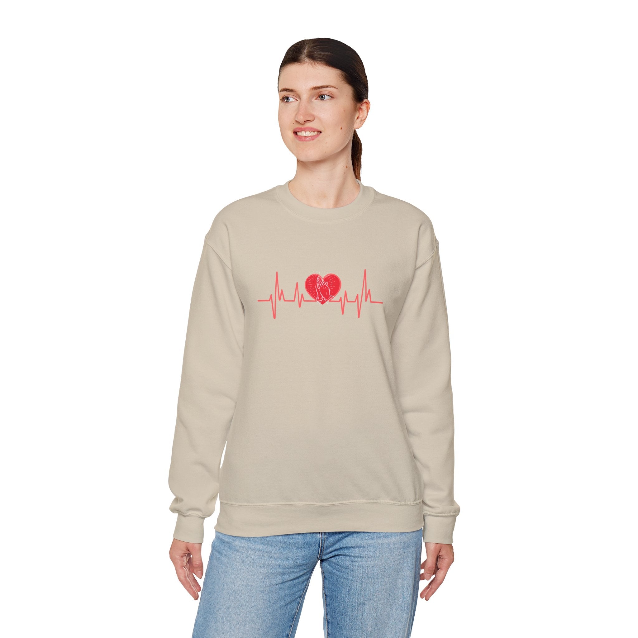 Woman wearing a beige sweatshirt with a red heart and line design on a white background