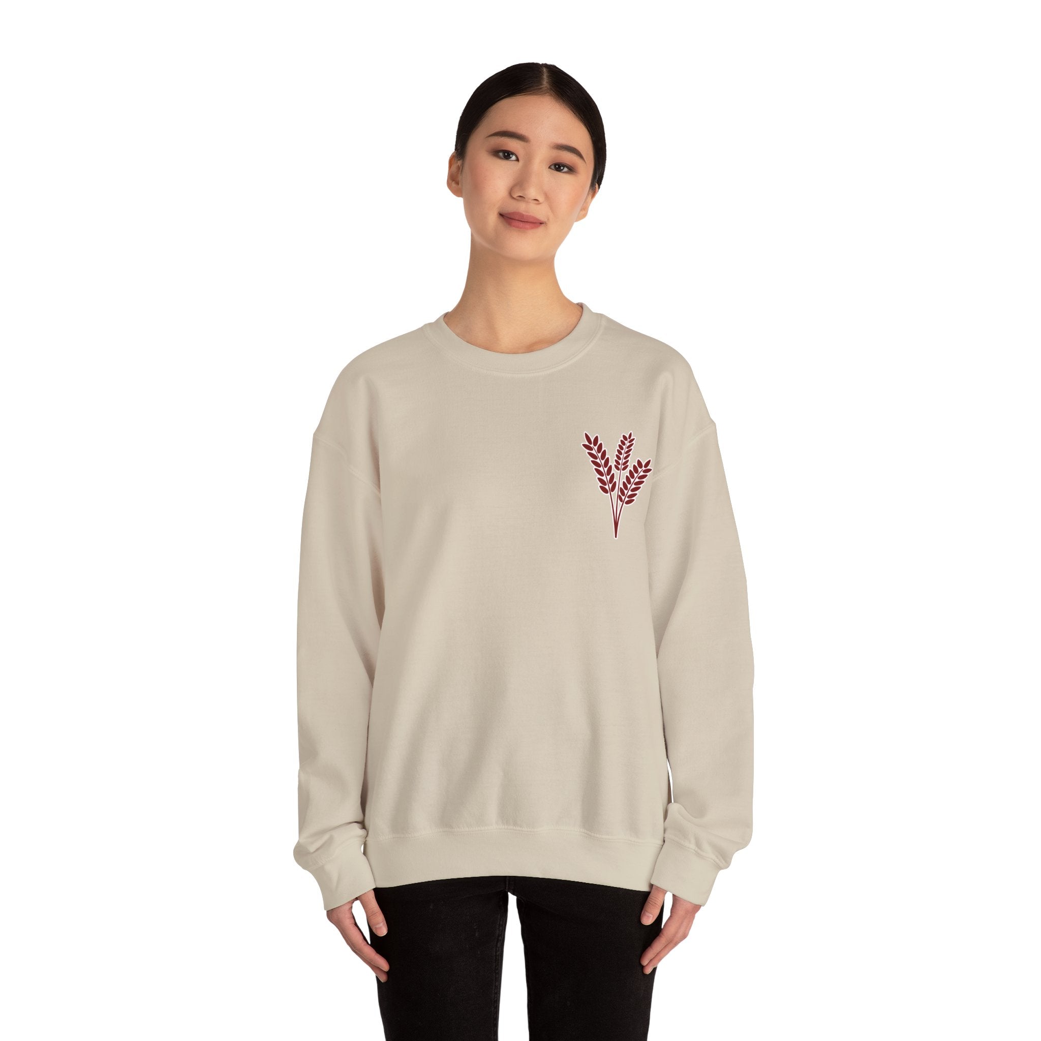 Person wearing a beige sweatshirt with a red leaf design on a white background