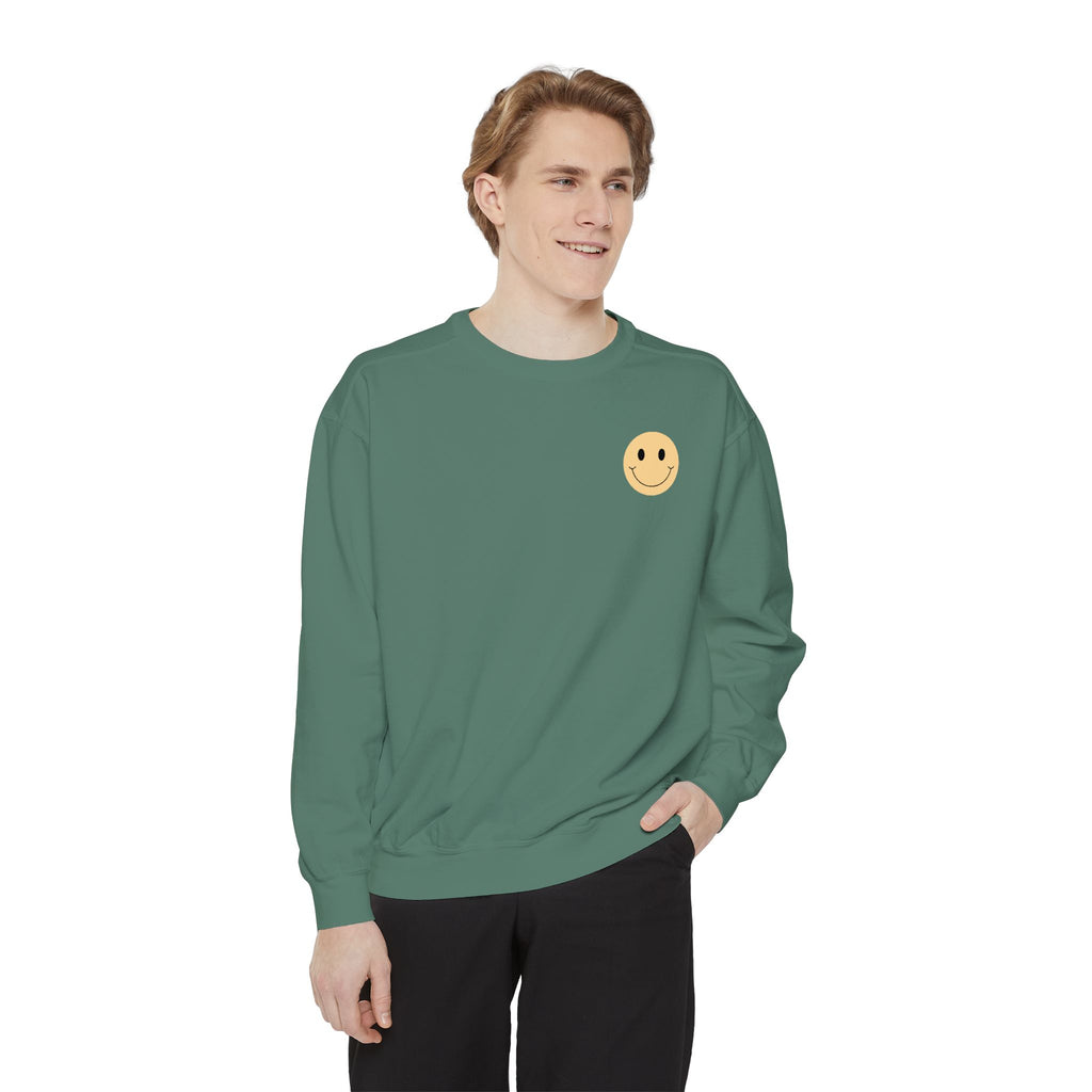 Person wearing a green sweatshirt with a smiley face emblem on a white background