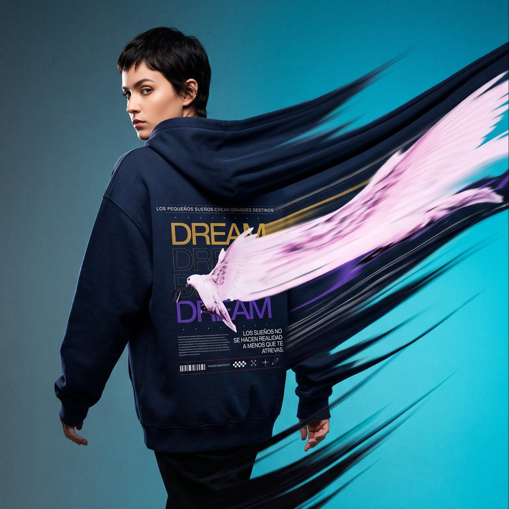 A model walks away wearing a navy hoodie with a large graphic print on the back, featuring a white bird and the word 'DREAM'. The background is a studio gradient of gray to bright blue, with a stylized pink and black brushstroke graphic overlay behind the model.