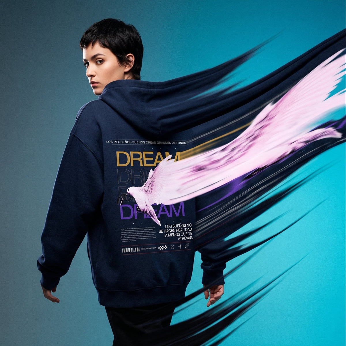 A model walks away wearing a navy hoodie with a large graphic print on the back, featuring a white bird and the word 'DREAM'. The background is a studio gradient of gray to bright blue, with a stylized pink and black brushstroke graphic overlay behind the model.