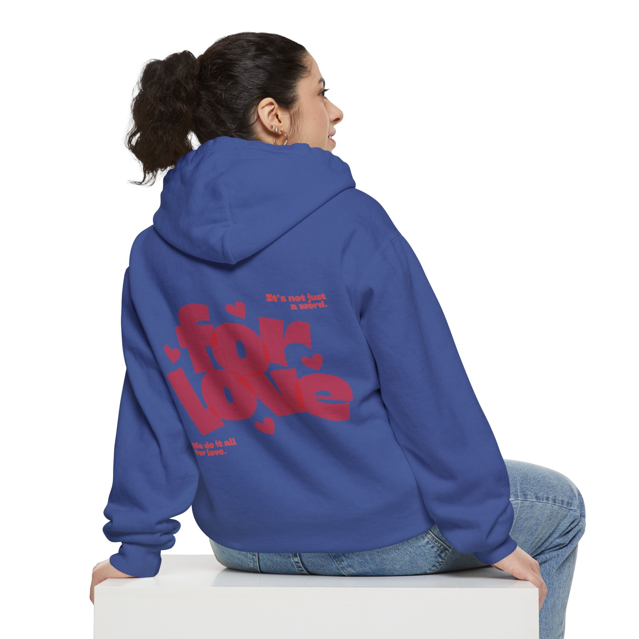 Person wearing a blue hoodie with red text on the back, sitting on a white block against a white background