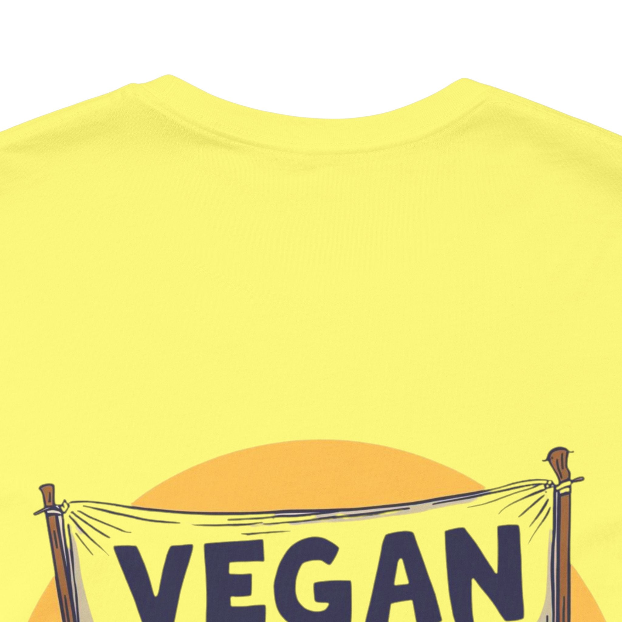 Yellow t-shirt with 'VEGAN' text and banner design on a white background