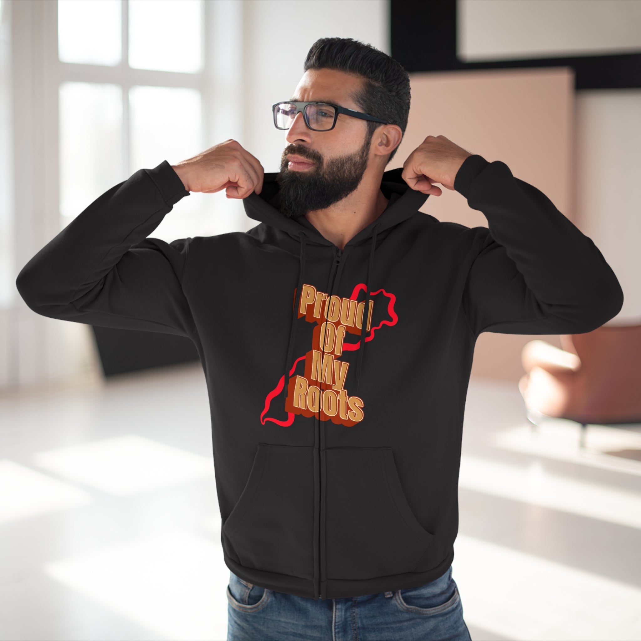 Man wearing a black hoodie with 'Proud of My Roots' text and graphic, indoors.