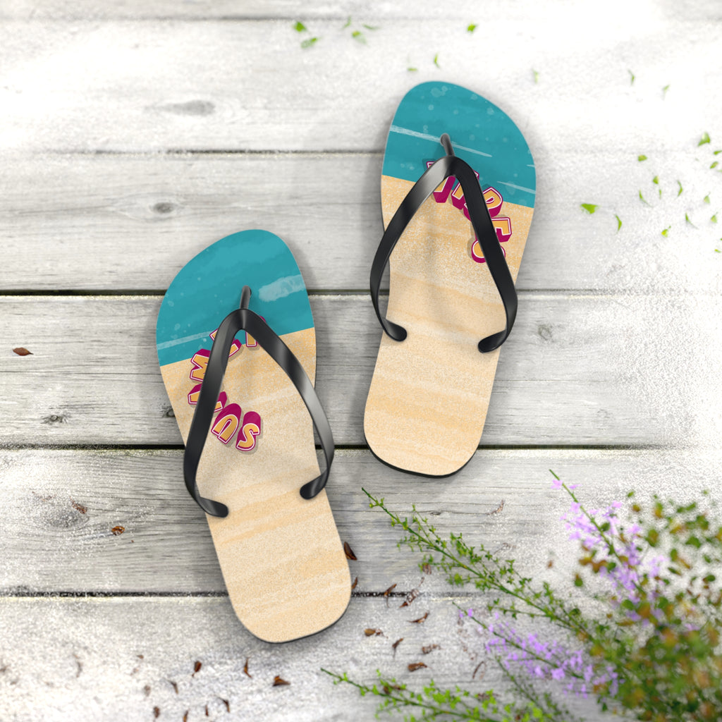 Pair of flip-flops with blue and beige soles on a wooden surface with flowers.