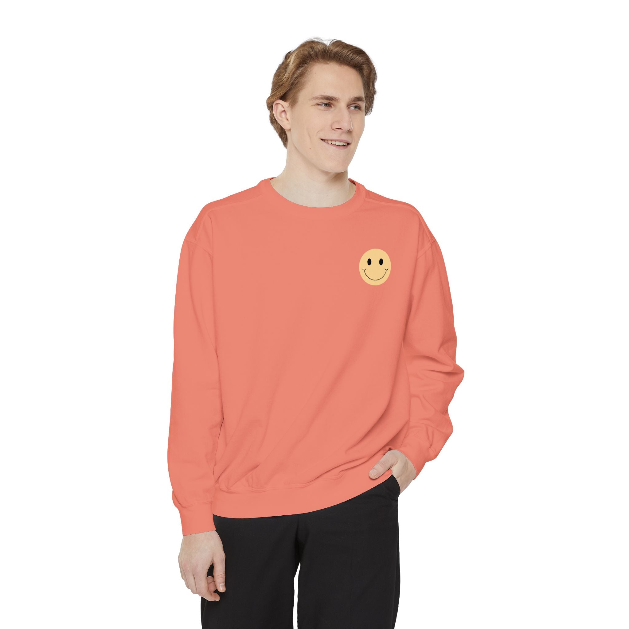 Person wearing a coral sweatshirt with a smiley face emblem on a white background