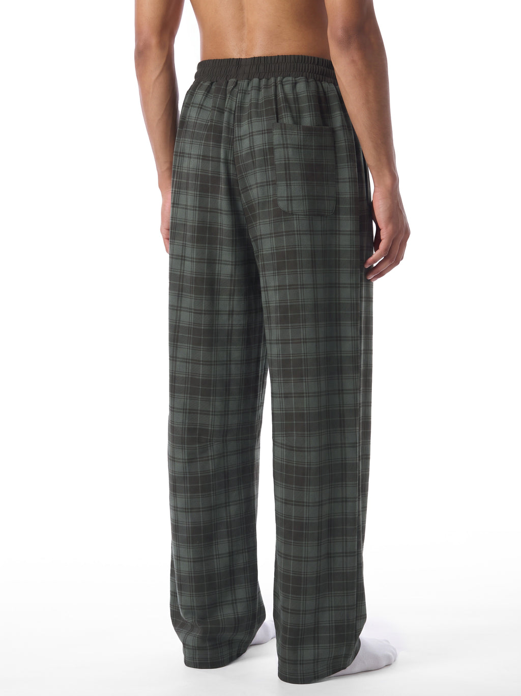 A man shown from the back wearing dark green and gray plaid lounge pants, photographed against a plain white studio background.
