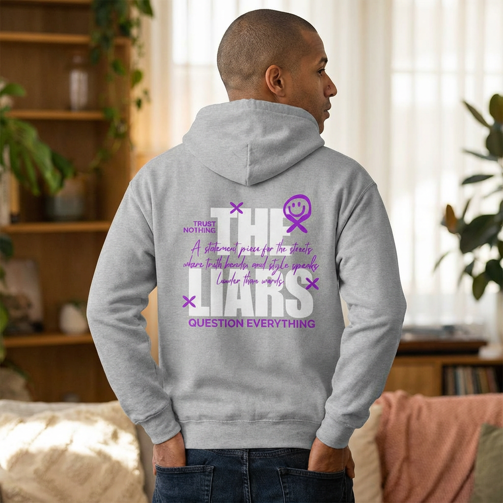 Person wearing a gray hoodie with text and graphics on the back, standing in a room with plants and furniture.