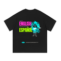A black short-sleeve t-shirt shown flat against a white background, featuring a colorful graphic on the front with the text 'I SPEAK ENGLISH PERO ME ENJOY EN ESPAÁOL' and a cartoon character made of scribbled lines. The brand name 'SHOWYOURIDENTITY' is printed below the graphic.