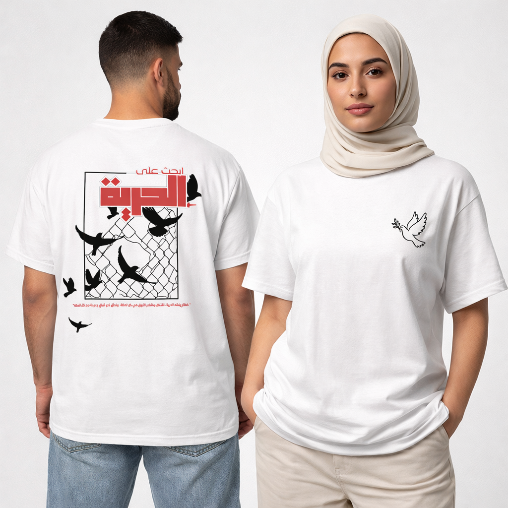 A man and a woman modeling white graphic t-shirts against a light gray studio background. The man shows the back of the shirt with a large black bird and Arabic text graphic, while the woman shows the front with a small black dove graphic on the chest. 
قميص أبيض عليه حمامة تحمل غصن الزيتون في الأمام، وخلفية طيور سوداء تحطم سياجًا معدنيًا مع عبارة ابحث على الحرية، تصميم ShowYourWisdom عن السعي نحو الحرية والانعتاق.
"اكسر القفص، وطر."

"ShowYourWisdom، ابحث على الحرية."

"الحرية ليست حلمًا، بل قرارًا."
