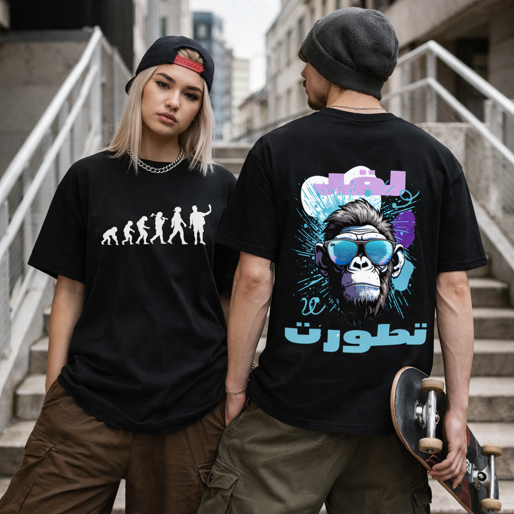 Two models wearing black graphic t-shirts in an outdoor urban setting with concrete stairs. The model on the left shows the front of the shirt with a white evolution graphic, while the model on the right shows the back of the shirt with a colorful gorilla graphic, sunglasses, and stylized text.
قميص أسود عليه تسلسل تطور الإنسان من القرد إلى شخص يحمل هاتفًا، وخلفية بوجه شمبانزي يرتدي نظارات مع عبارة لقد تطورت، تصميم ساخر من مجموعة ShowYourIdentity.
"لقد تطورنا... لكن انحنينا أكثر!"
"ShowYourIdentity، ارفع رأ