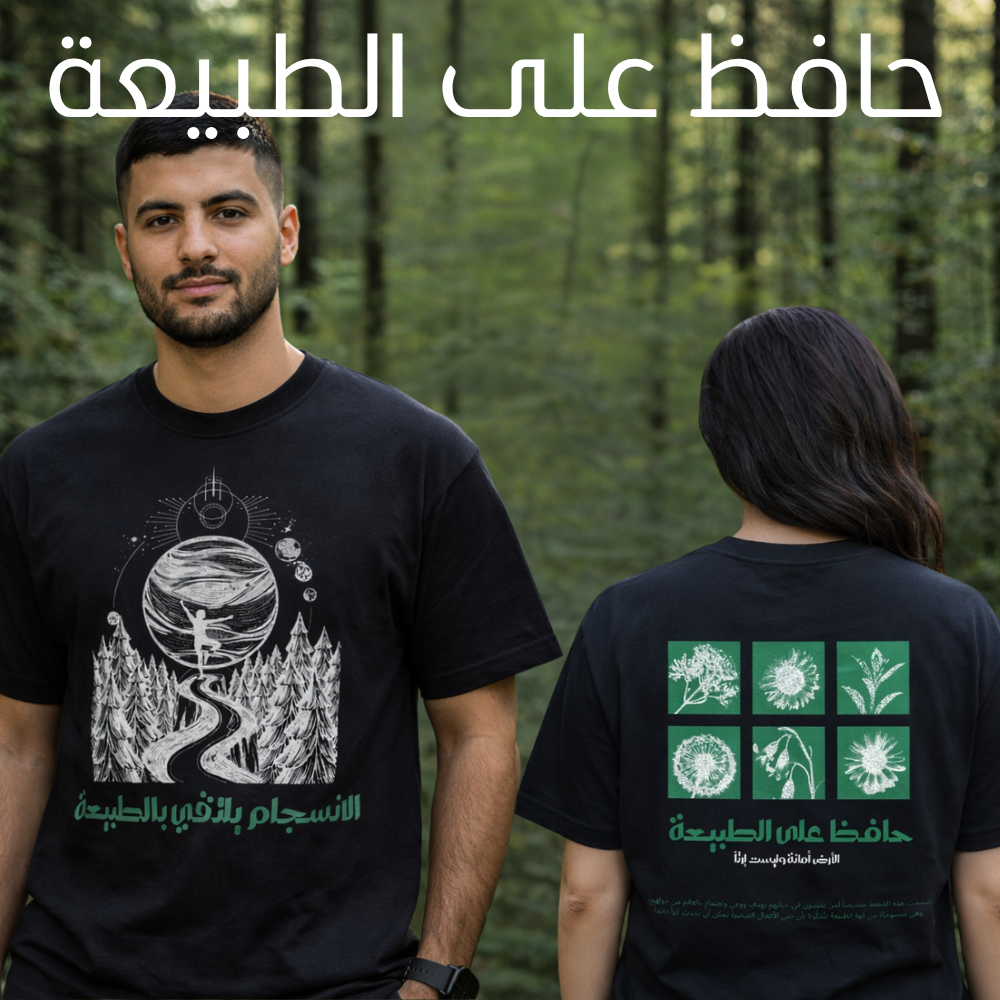 A man and a woman standing outdoors in a forest, both wearing black graphic T-shirts. The man shows the front of the shirt with a white and green nature-themed print and Arabic text.
قميص أسود عليه رسم طريق بين الأشجار نحو كوكب في السماء مع عبارة الانسجام بالذات في الطبيعة، وخلفية نباتات وزهور مع عبارة حافظ على الطبيعة، تصميم ShowYourNature عن حماية البيئة والانسجام مع الأرض.