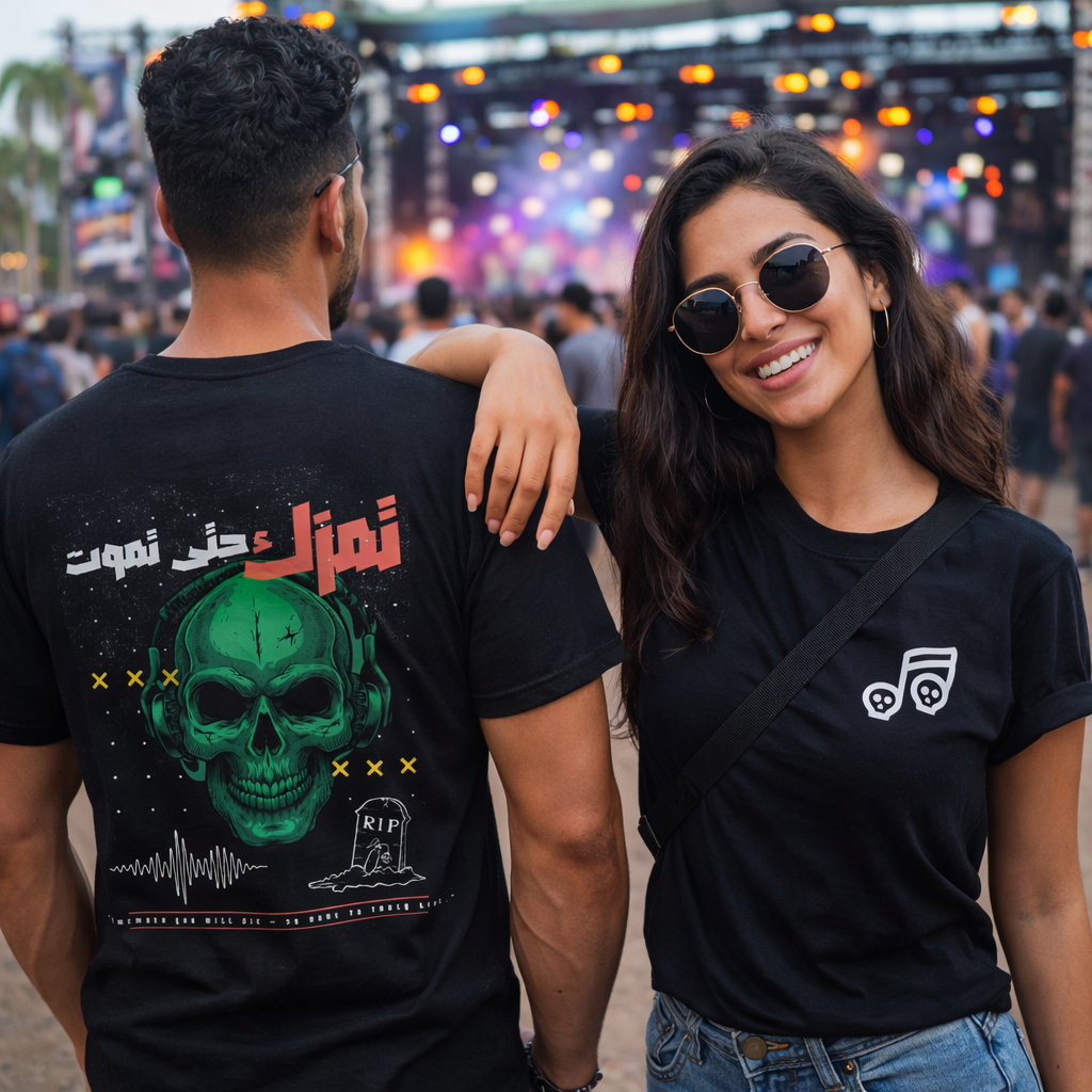 Two people wearing black t-shirts with graphic designs at a concert.
Black t-shirt front skull music note design, back green skull headphones Arabic text Play music until you die, ShowYourVibes collection, dark music streetwear, festival fashion.
“Play it loud — till death.”“ShowYourVibes, show your rhythm.”“Music never dies.”“Live by the beat, die by the sound.”