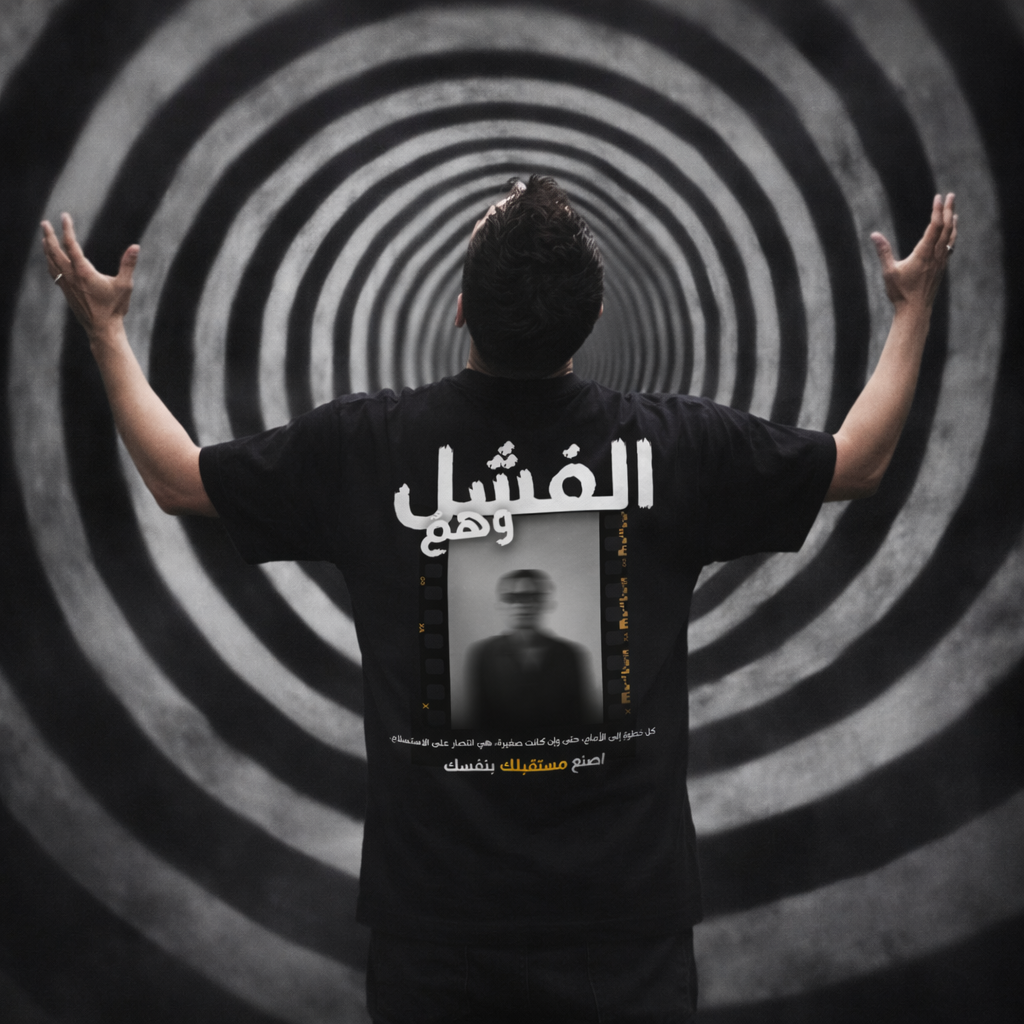 A man stands with his back to the camera wearing a black t-shirt featuring a large white Arabic graphic and a central photo print on the back. He is posed in front of a black and white spiral tunnel background.
قميص أسود عليه عبارة الفشل وهم وصورة ضبابية لشخص، مع اقتباس كل خطوة إلى الأمام هي انتصار على الاستسلام، تصميم ShowYourWisdom عن الإصرار والتغلب على الفشل.
"الفشل ليس نهاية، بل بداية جديدة."

"ShowYourWisdom، اصنع مستقبلك بنفسك."

"كل سقوط هو خطوة نحو النهوض."

"الوهم الوحيد هو أن تتوقف عن المحاولة."