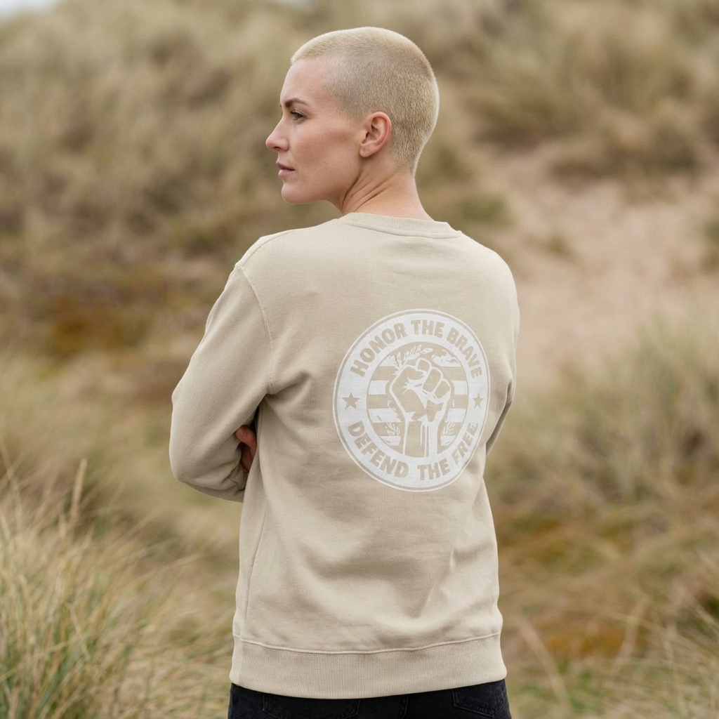 Person wearing a beige sweatshirt with a logo and text in a natural setting